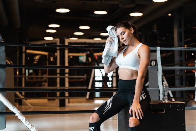 fit Mädchen hält Handtuch und ruht sich im Fitnessstudio aus