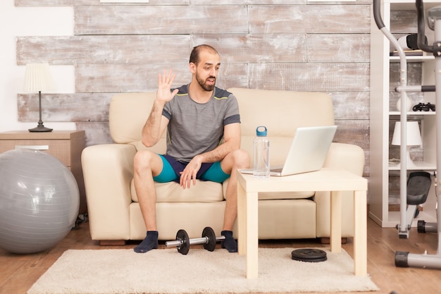 Fit Mann in einem Videoanruf mit Personal Trainer während der globalen Pandemie.