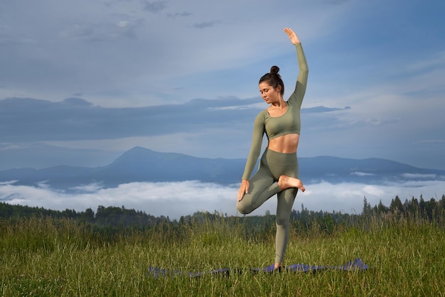 Fitness-frau macht yoga-übungen inmitten grüner natur