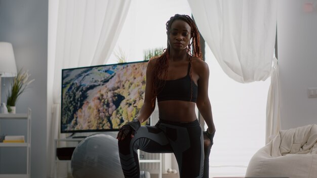 Fitness-Frau mit dunkler Haut beim Yoga-Training im Wohnzimmer