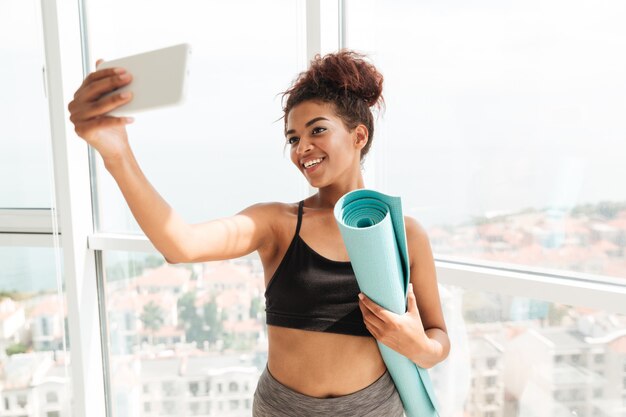 Fitnessfrau, die selfie auf Smartphone macht und lächelt