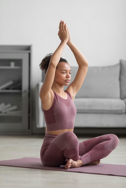 Fitnessfrau, die Yoga auf einer Yogamatte zu Hause tut