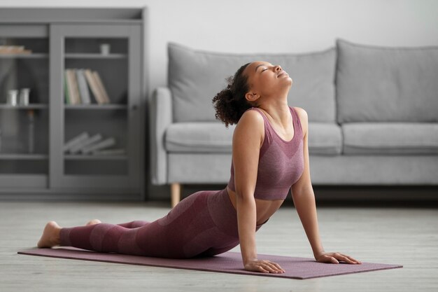 Fitnessfrau, die Yoga auf einer Yogamatte zu Hause tut