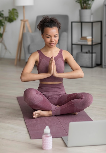 Kostenloses Foto fitnessfrau, die yoga auf einer yogamatte zu hause tut