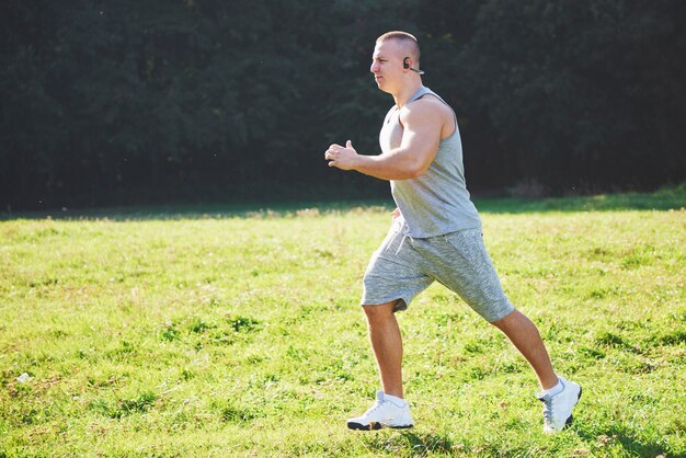 Fitnessmannathlet, der in der Natur während des Sonnenuntergangs joggt.