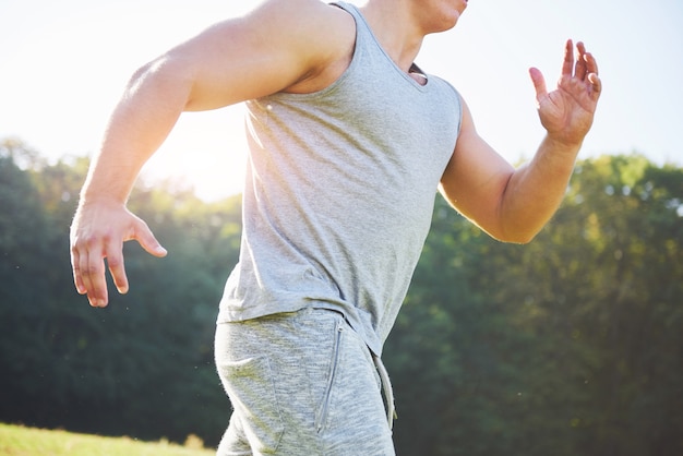 Fitnessmannathlet, der in der Natur während des Sonnenuntergangs joggt.