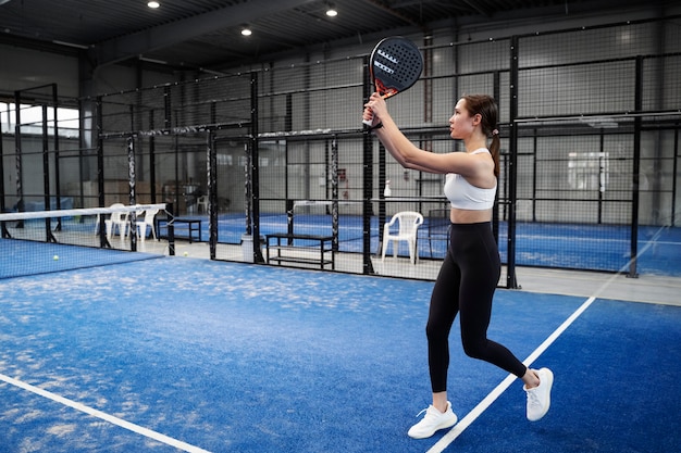 Kostenloses Foto fitte frau, die paddle-tennis spielt, voller schuss