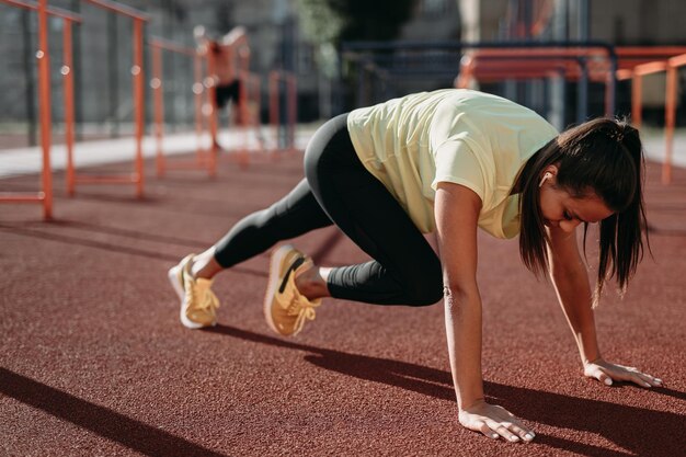 Fitte Frau im Sportoutfit trainiert Bauchmuskeln im Stadtstadion