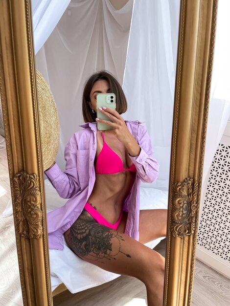 Fitte gebräunte Frau mit perfektem Körper macht Foto-Selfie am Telefon im Spiegel zu Hause