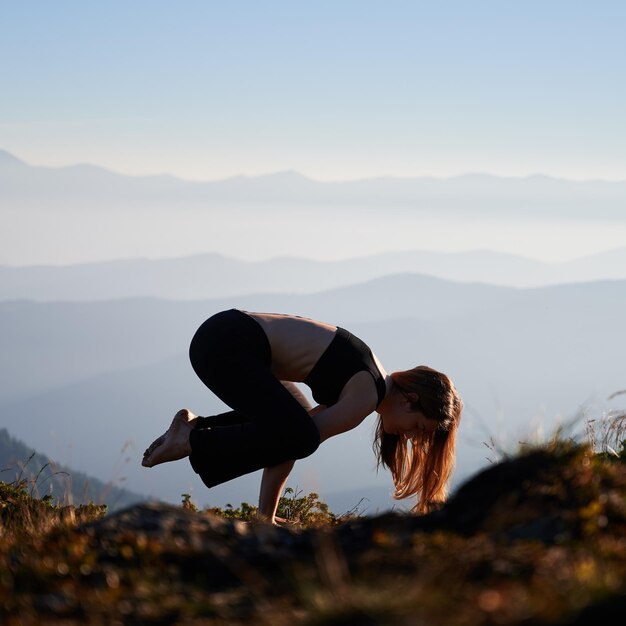 Fitte junge Frau, die Yoga-Übungen in den Bergen macht