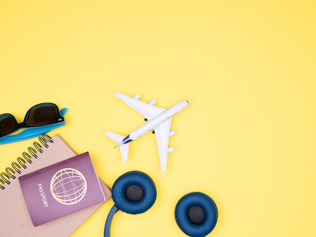 Flach auf gelbem Hintergrund von Flugzeug, Kopfhörern, Reisepass und Sonnenbrille. Exemplar verfügbar