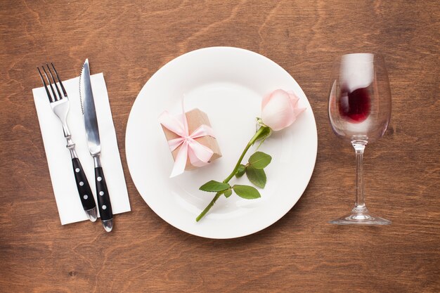 Flach lag Rose und Geschenk auf einem Teller