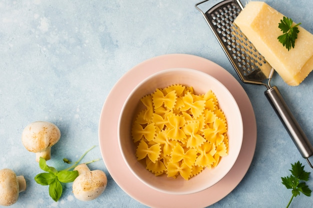 Kostenloses Foto flach lag ungekochte farfalle in schüssel mit parmesan