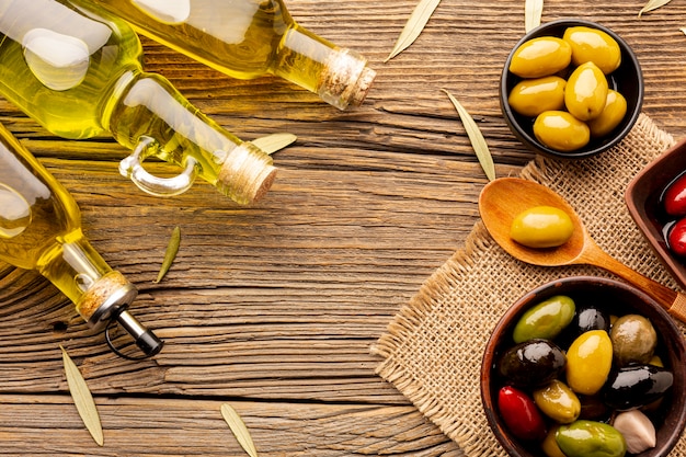 Flach legen Oliven in Schalen Ölflaschen und Blätter auf Textilmaterial