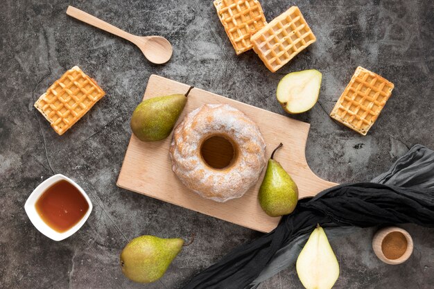 Flache Donuts auf Schneidebrett mit Birnen und Waffeln