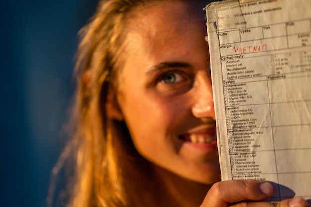 Kostenloses Foto flache fokusaufnahme einer frau, die die hälfte ihres gesichts hinter einem papier versteckt