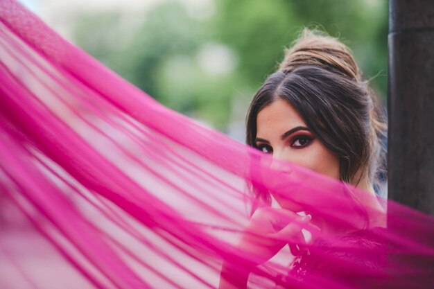 Flache Fokusaufnahme einer jungen schönen kaukasischen Frau in einem rosa Kleid, die vor der Kamera posiert