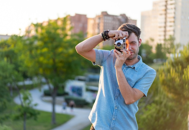 Flache Fokusaufnahme eines jungen Mannes, der ein Foto im Park macht