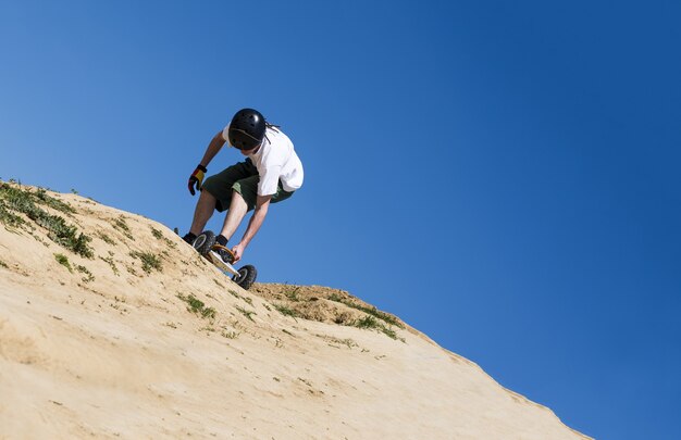 Flache Fokusaufnahme eines Jungen mit einem Mountainboard in einem Feldweg