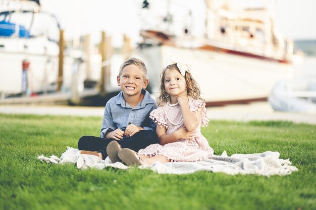 Flache Fokusaufnahme eines kleinen blonden Mädchens mit einem Jungen auf dem Gras