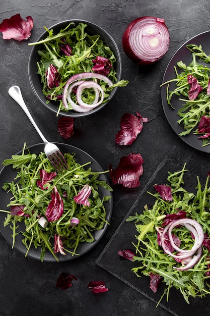 Flache frische Salate auf dunkle Teller legen