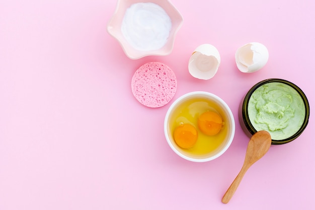 Flache Lage der Creme und der Eier auf rosa bacground mit Kopienraum