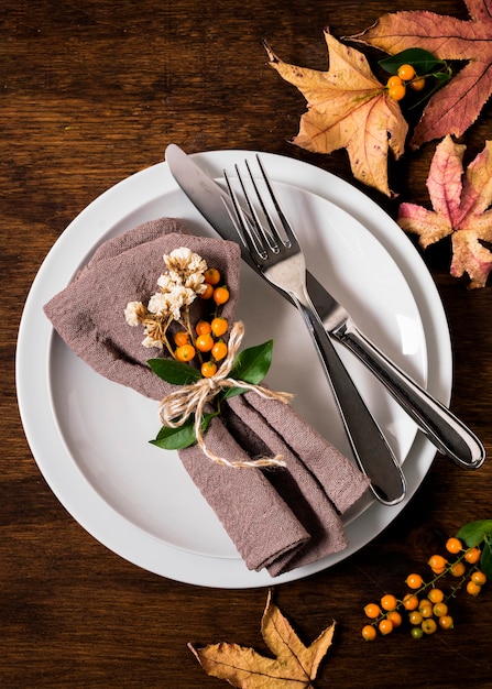 Flache Lage der Erntedank-Tischanordnung mit Besteck und Herbstlaub