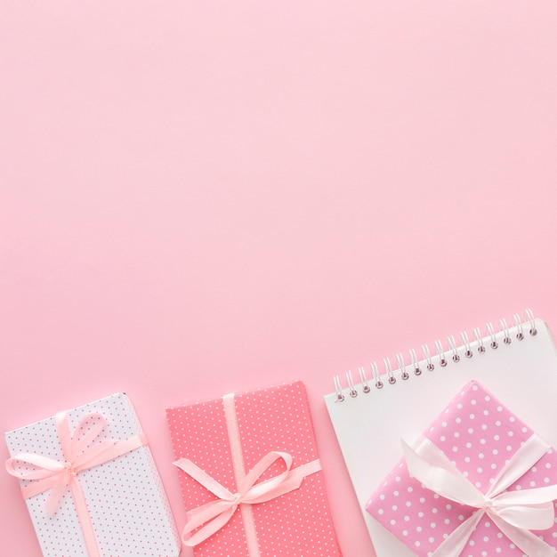 Flache Lage der rosa Geschenke mit Notizbuch und Kopienraum