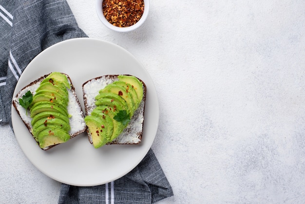 Flache Lage des Avocadotoasts auf Platte mit Kräutern und Gewürzen