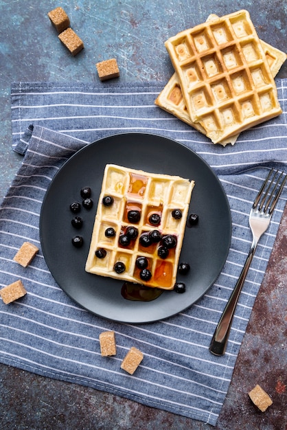 Flache Lage des Honigs bedeckte Waffeln auf Platte mit Früchten