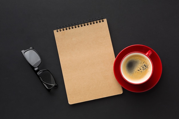 Flache Lage des Notizbuches und der Kaffeetasse auf Arbeitsschreibtisch