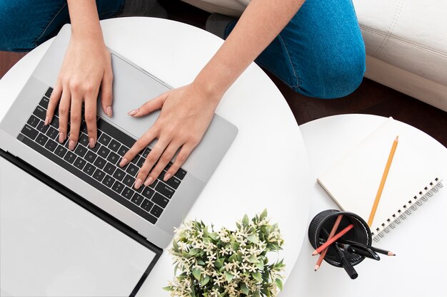 Flache Lage des Schreibtisches mit Frau, die am Laptop arbeitet