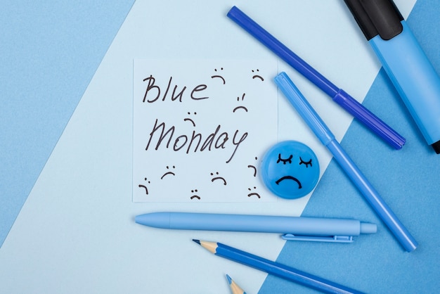 Flache Lage des traurigen Gesichts mit Stiften und Markierung für blauen Montag