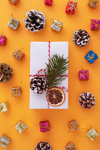 Flache Lage einer weiß dekorierten Geschenkbox und Weihnachtsschmuck auf Orange