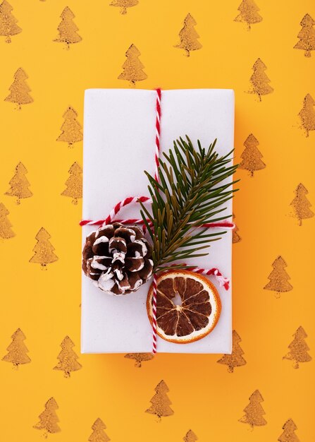 Flache Lage einer weiß verzierten Geschenkbox, Weihnachtsbaummuster im orangefarbenen Hintergrund