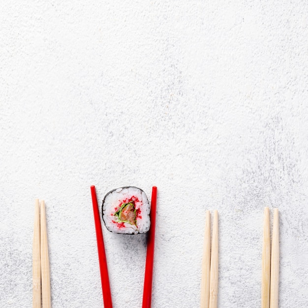 Flache Lage maki Sushirolle und Essstäbchen mit Kopienraum