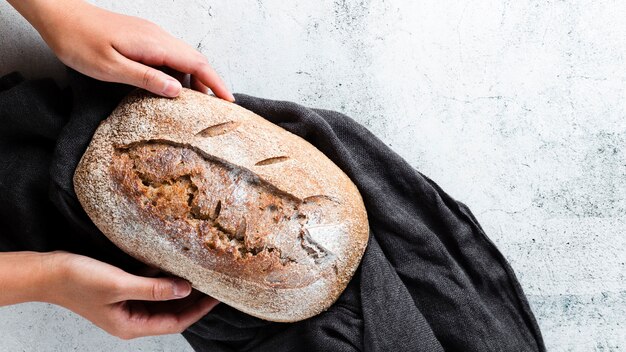 Flache Lage von den Händen, die Brot auf Stoff halten