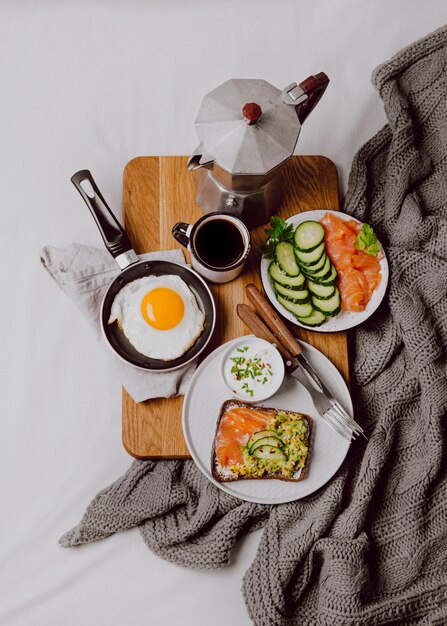 Flache Lage von Frühstücksbrötchen auf dem Bett mit Spiegelei und Toast