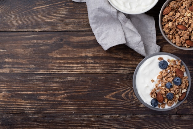Flache Lage von Frühstücksflocken mit Blaubeeren und Joghurt