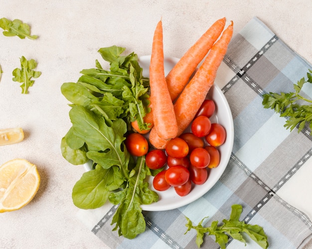 Flache Lage von Karotten und Tomaten auf Platte