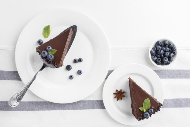 Flache Lage von Schokoladenkuchenscheiben auf Tellern mit Blaubeeren