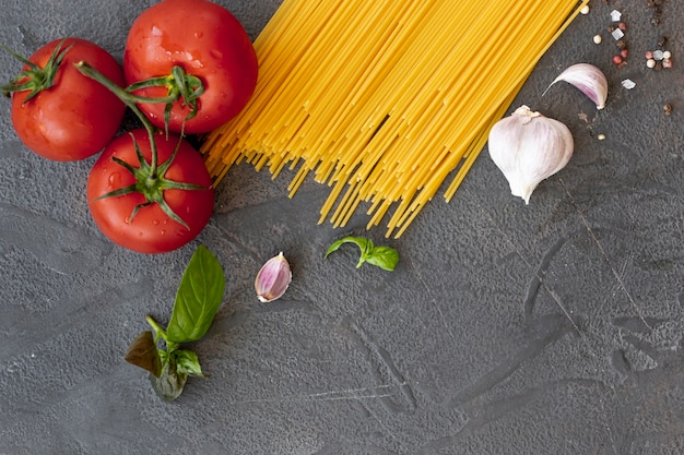 Kostenloses Foto flache lage von spaghettis, von tomaten und von knoblauch auf einfachem hintergrund