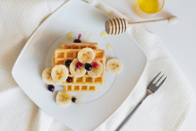 Flache Lage von Waffeln mit Früchten und Honig