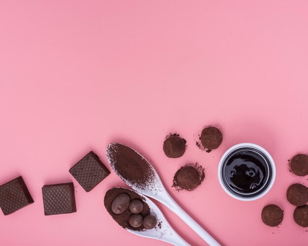 Flache Lagemischung von Schokoladenbonbons auf rosa Hintergrund mit Kopienraum