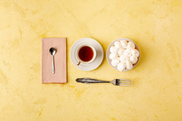 Flache Lagenzusammenstellung mit Tee und Kuchen auf gelbem Hintergrund