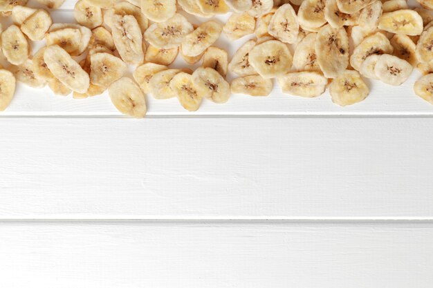 Flache lagezusammensetzung mit bananenscheiben auf weißem hintergrund; platz für text. trockenfrüchte als gesunder snack