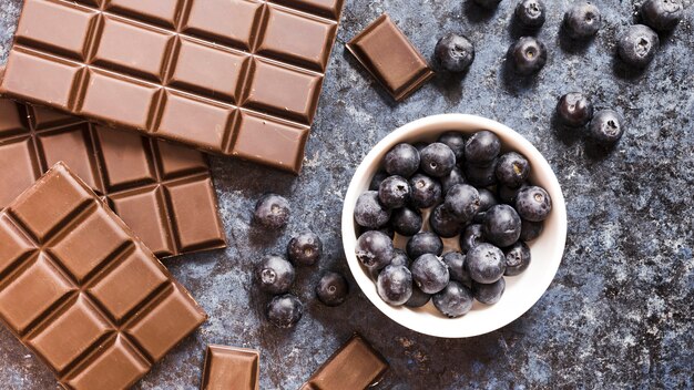 Flache Laienschokolade und -blaubeeren auf Schmutztabelle