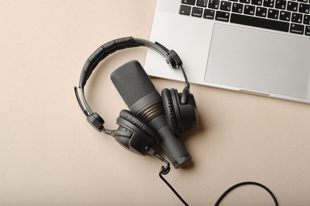 Flache Lay-Komposition mit Mikrofon für Podcasts und schwarzen Studiokopfhörern auf braunem Hintergrund mit Kaffee und Laptop, die Online-Bildungskonzept lernenxA