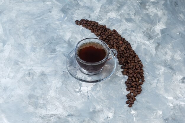 Flache legen Kaffeebohnen mit Tasse Kaffee auf hellblauem Marmorhintergrund. horizontaler freier Speicherplatz für Ihren Text