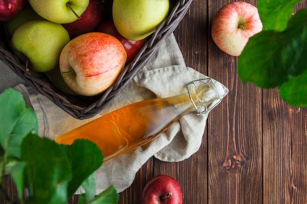 Flache legen Äpfel in Box mit Blättern und Apfelsaft auf Stoff und Holzhintergrund. horizontal